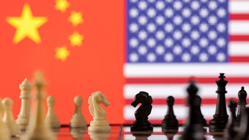 Chess pieces are seen in front of displayed China's and U.S. flags.