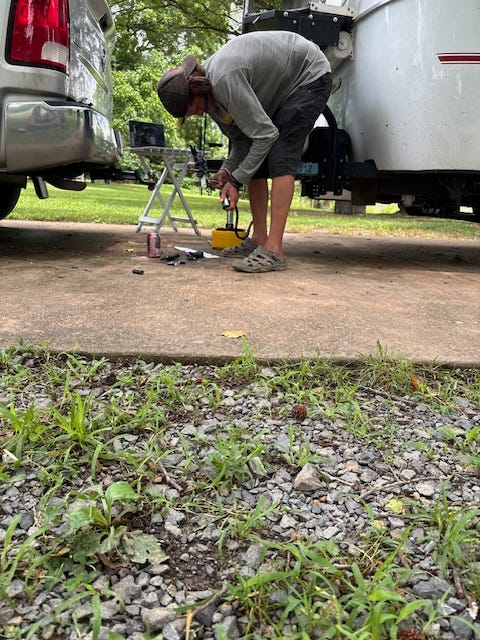 A young man bends forward, examining the parts of a hitch plug