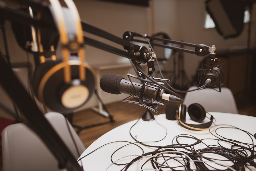 Podcasting setup with headphones, wires and professional microphones around a table.