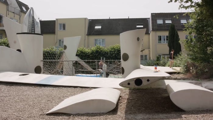 Pieces of wind turbine blades being reused on a playground as benches, a table, and posts connecting a net.