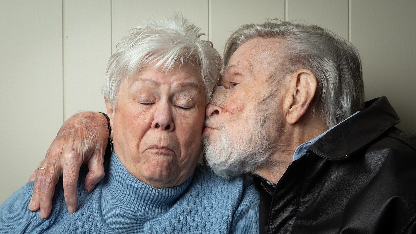 an old man gives his wife a peck on the cheek