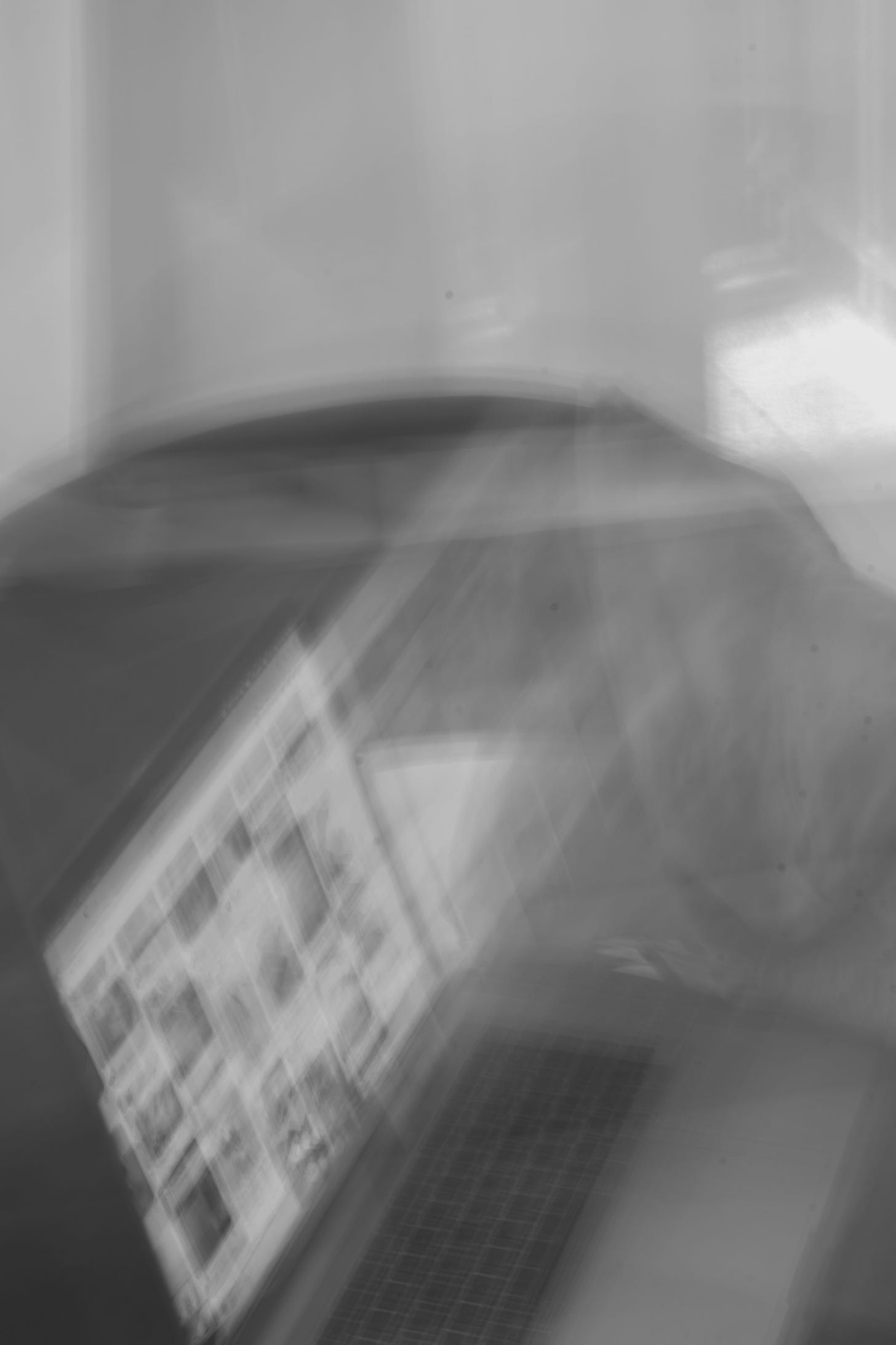 blurry b&w image of laptop on a bed