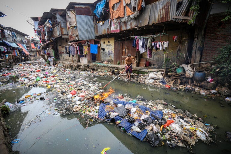 Homes of corrugated metal, rusted and draped in tattered fabrics, line a waterway filled with enough garbage that one could walk across it. From one of Indonesia's most polluted cities.