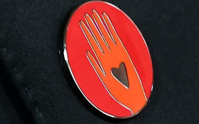A red pin with an orange hand, worn by some celebrities at the Academy Awards event on March 10, 2024, to show support for Palestinians in Gaza and call for a ceasefire in the Israel-Hamas war. (via X, formerly Twitter)