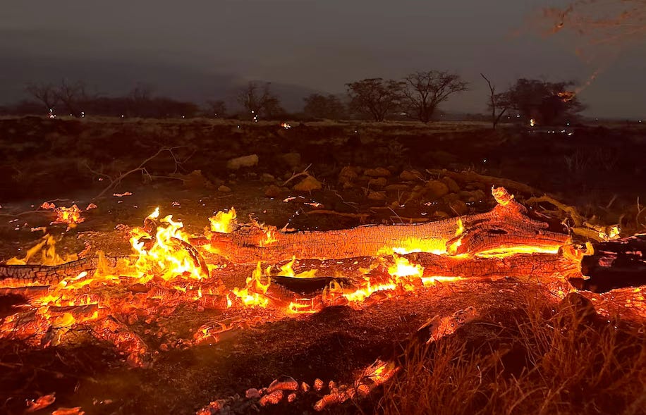 Embers glow and flames lick the ruins of Kihei, Hawaii.