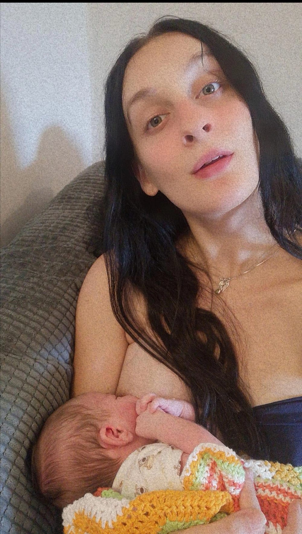 A young conscious mother breastfeeding her newborn baby
