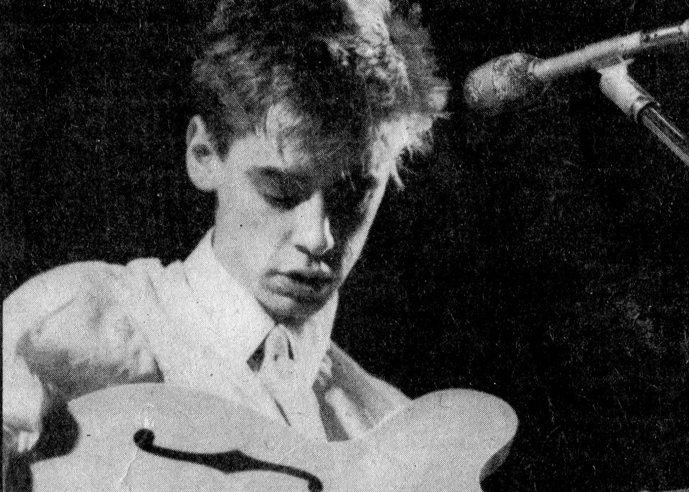 Close up of Nick Heyward on stage, holding a guitar.