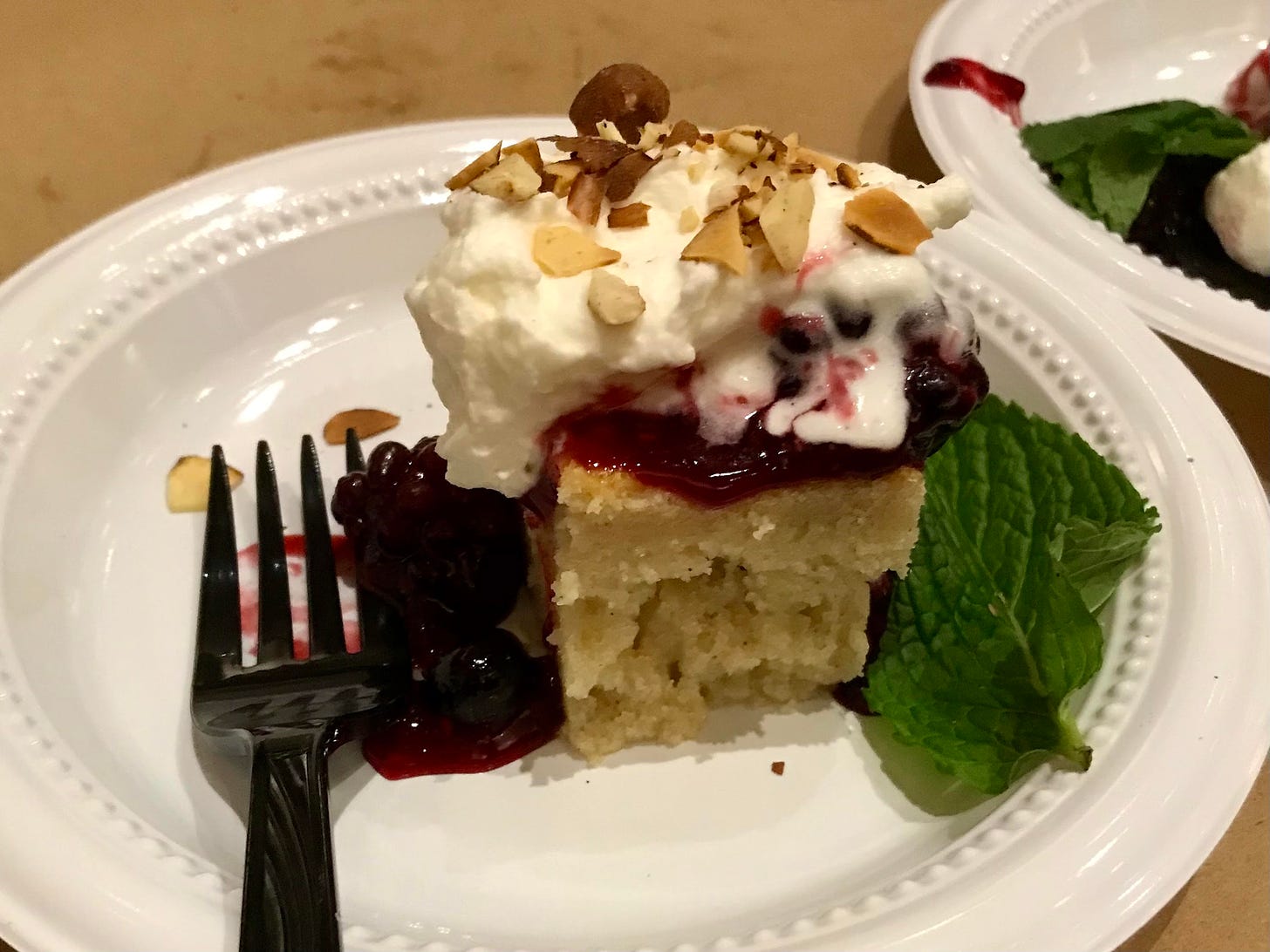 small bite of dense almond cake topped with flambéed berries, torched meringue, and toasted almonds