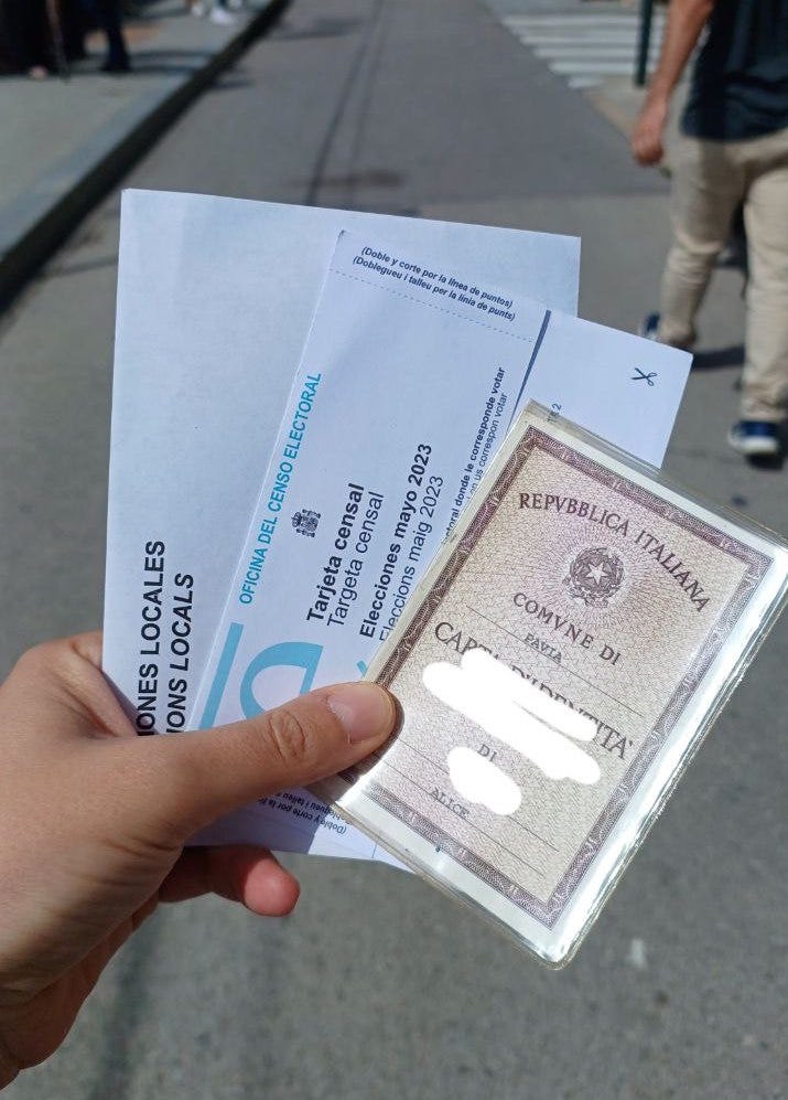 La mia mano che regge i tre documenti per votare in Spagna: la carta di identità, la tarjeta censal e la busta bianca con dentro il voto.