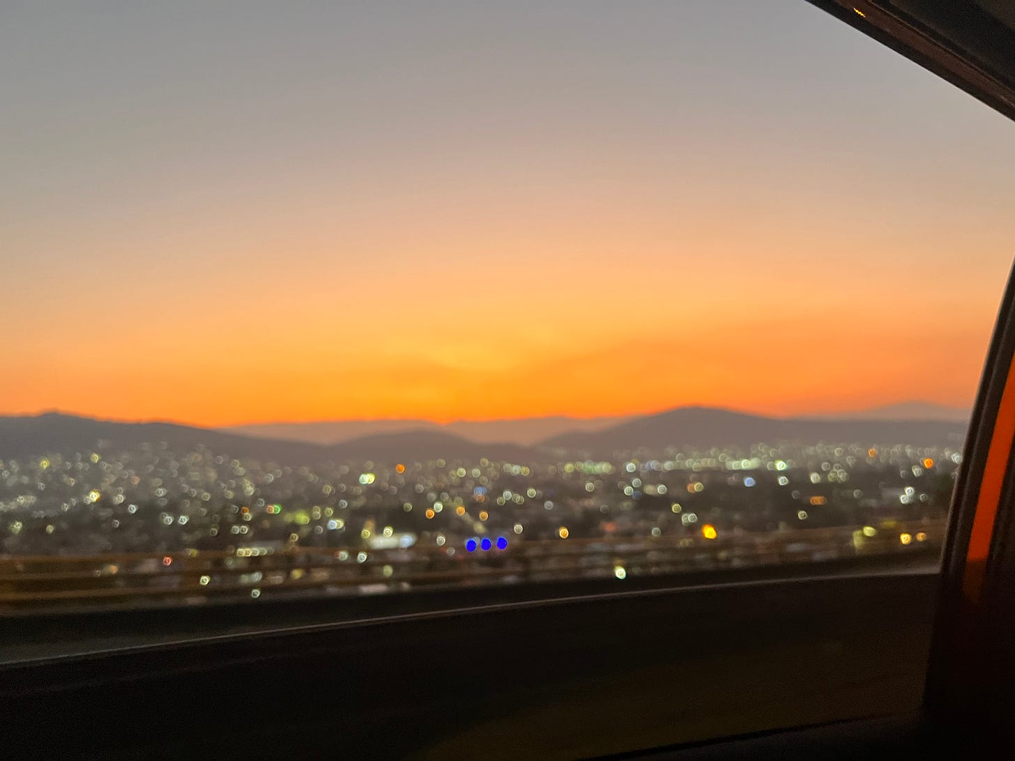 An out of focus shot of the sunset over the city, tinted an unnatural orange by smoke.