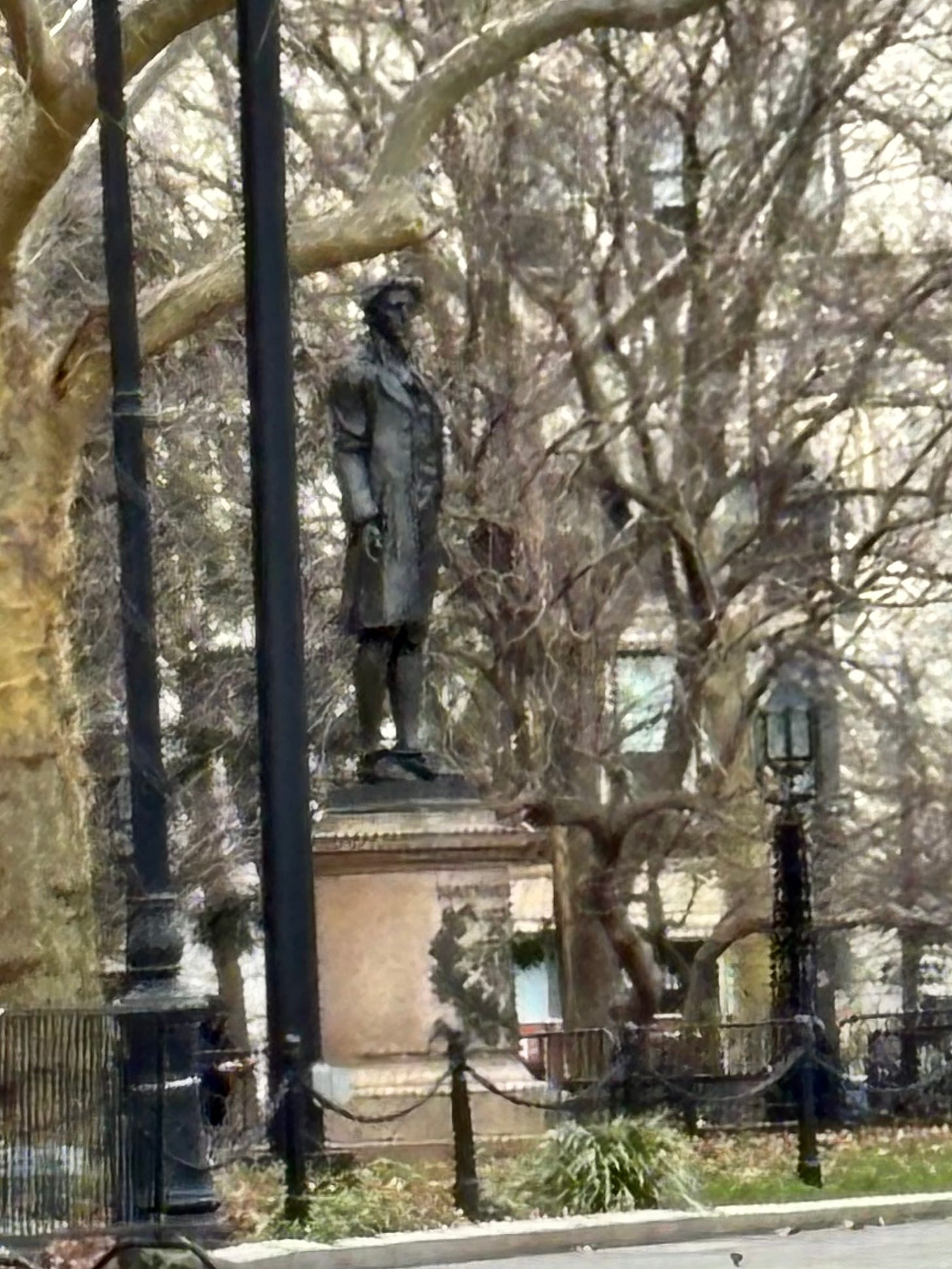A zoomed-in photo of the front of Hale's statue. A high fence is visible to his right, our left.