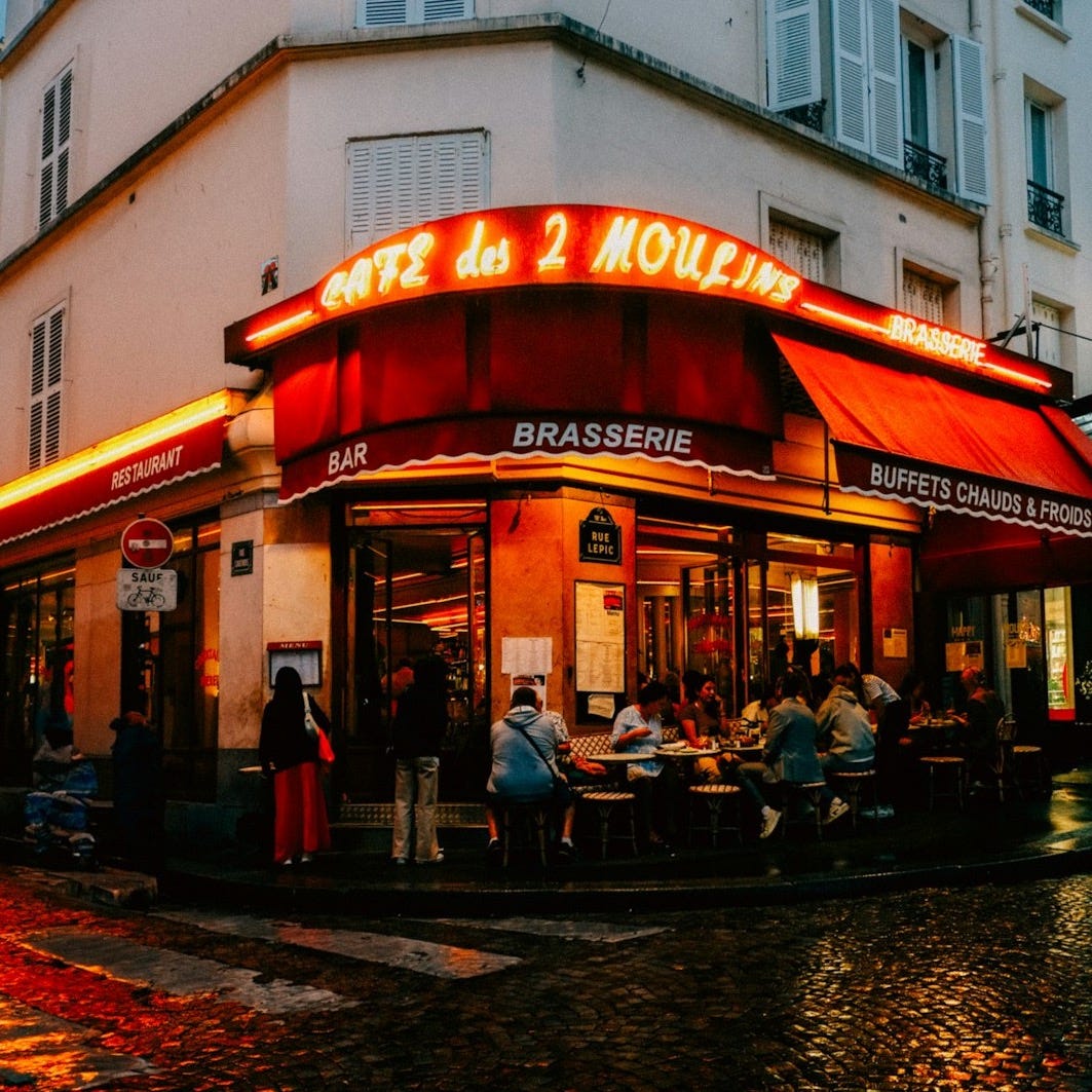 A restaurant with a red awning on a rainy day