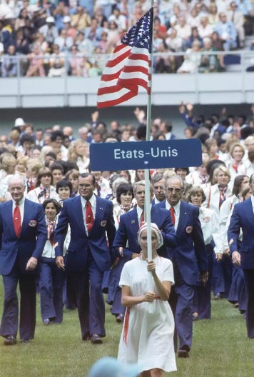 A person holding a flag and a group of people walking

Description automatically generated