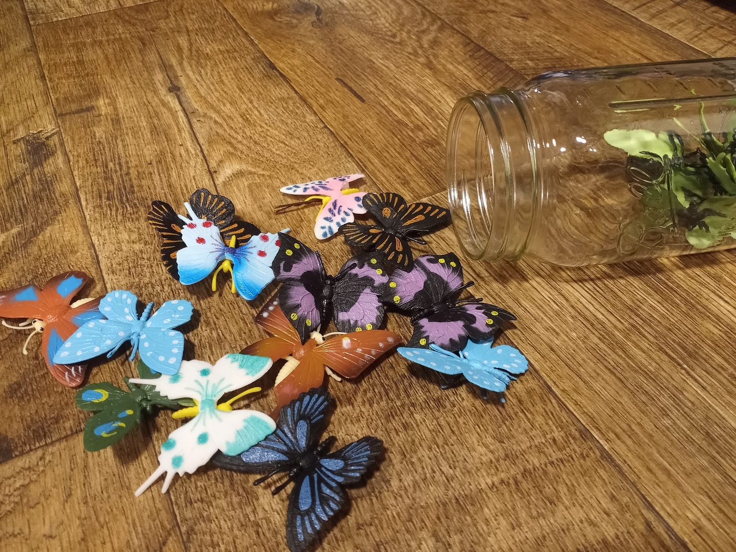 Plastic butterflies in a rainbow of colors spill out of a large mason jar