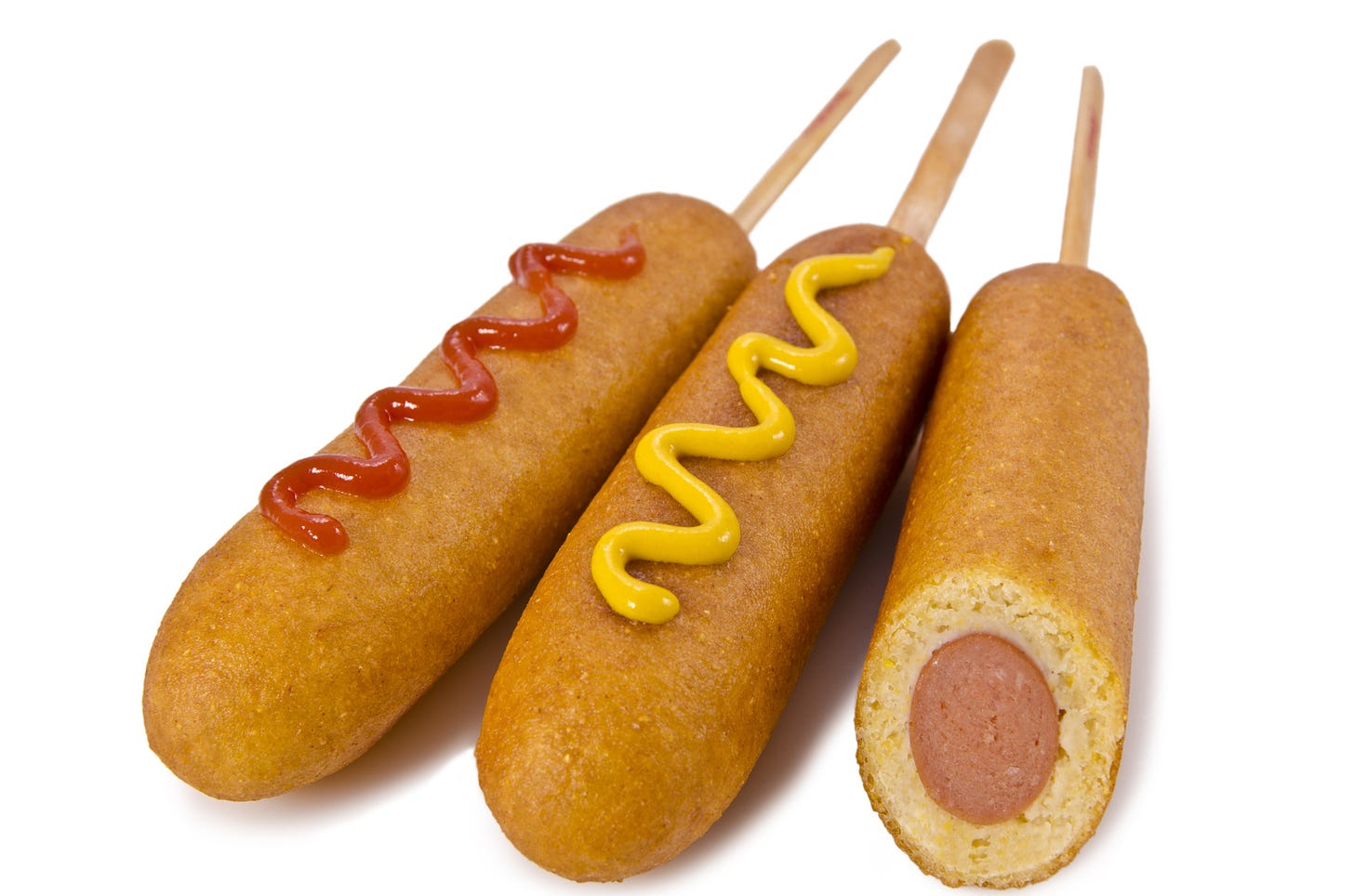 3 corndogs side by side with ketchup and mustard and a bite out of one.