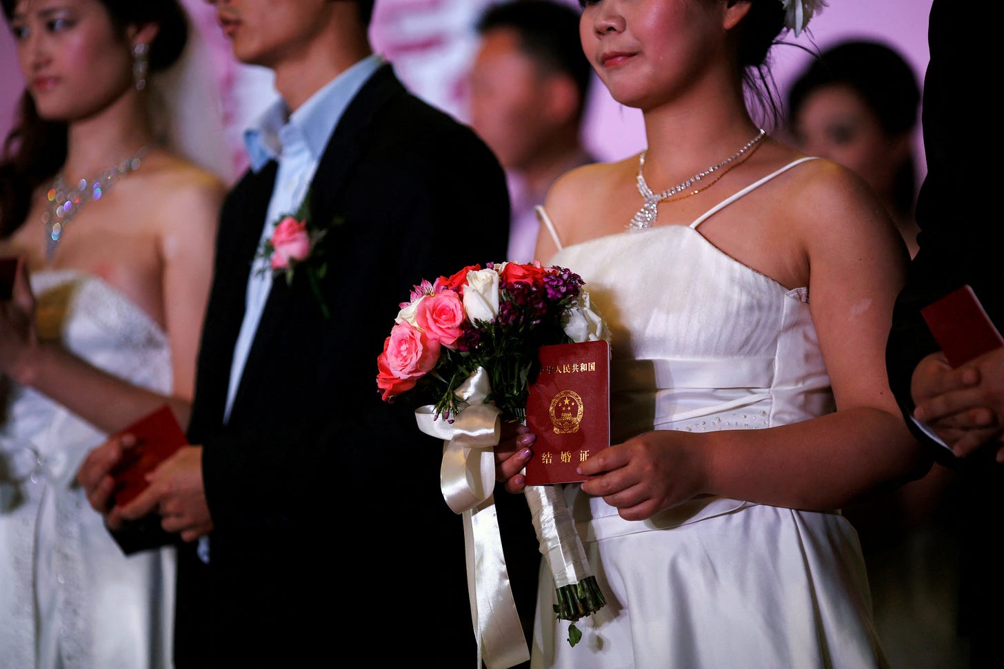 A woman holds her marriage certificate, as couples participate in a staged mass wedding in Shanghai