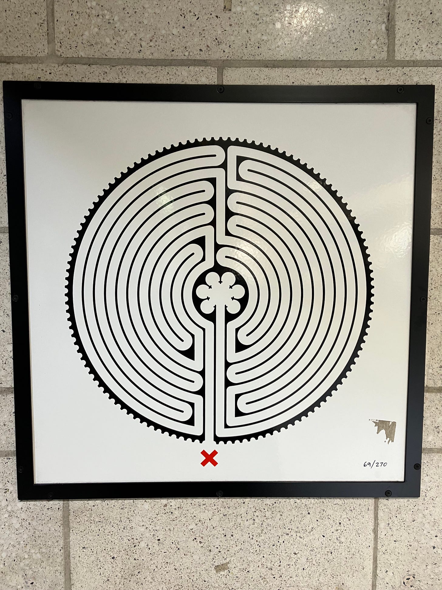 An image of a circuit labyrinth in the Chartes style, hung on a beige tiled wall