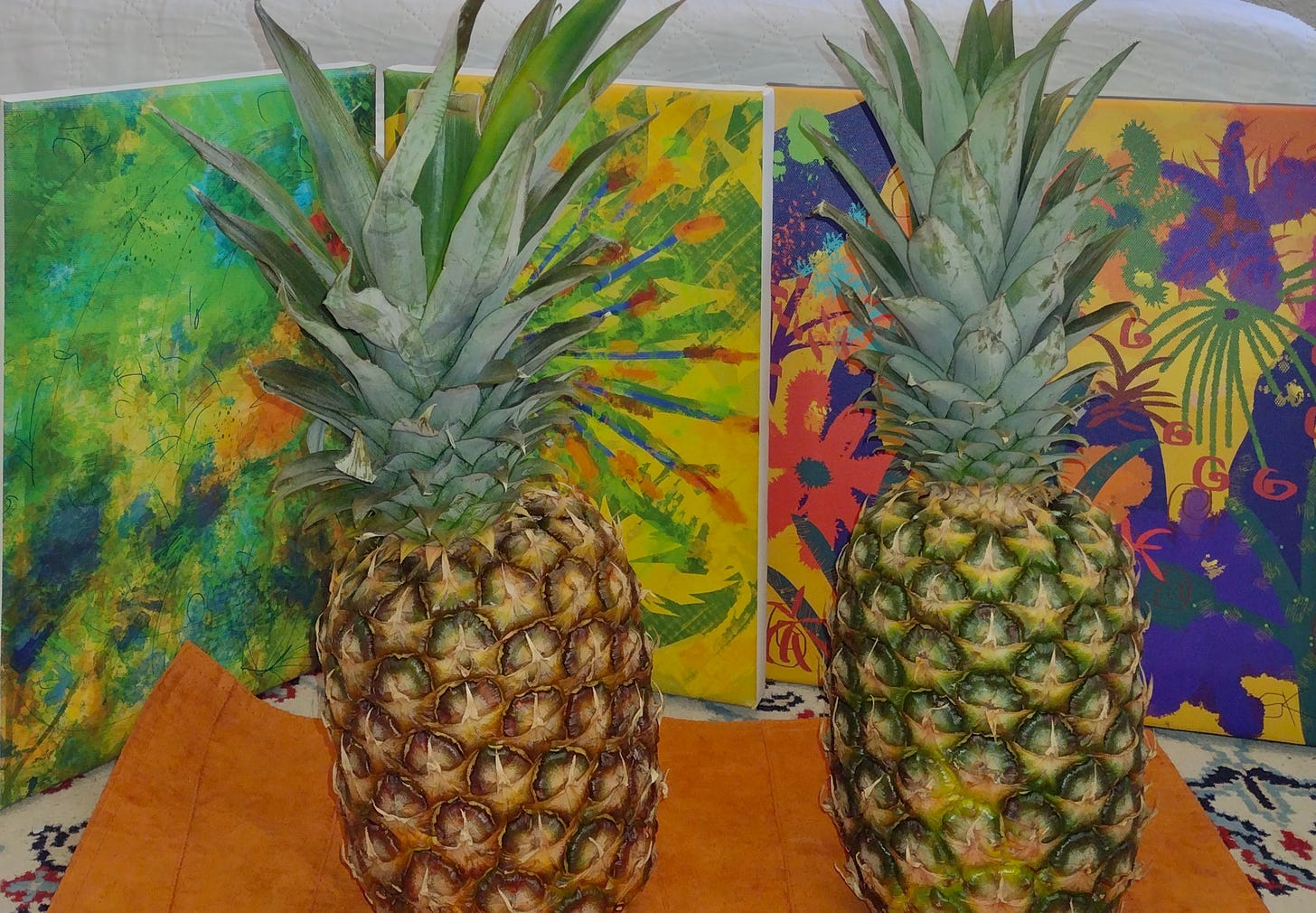 Colorful artwork by Sherry Killam of two upright pineapples against folding screens.