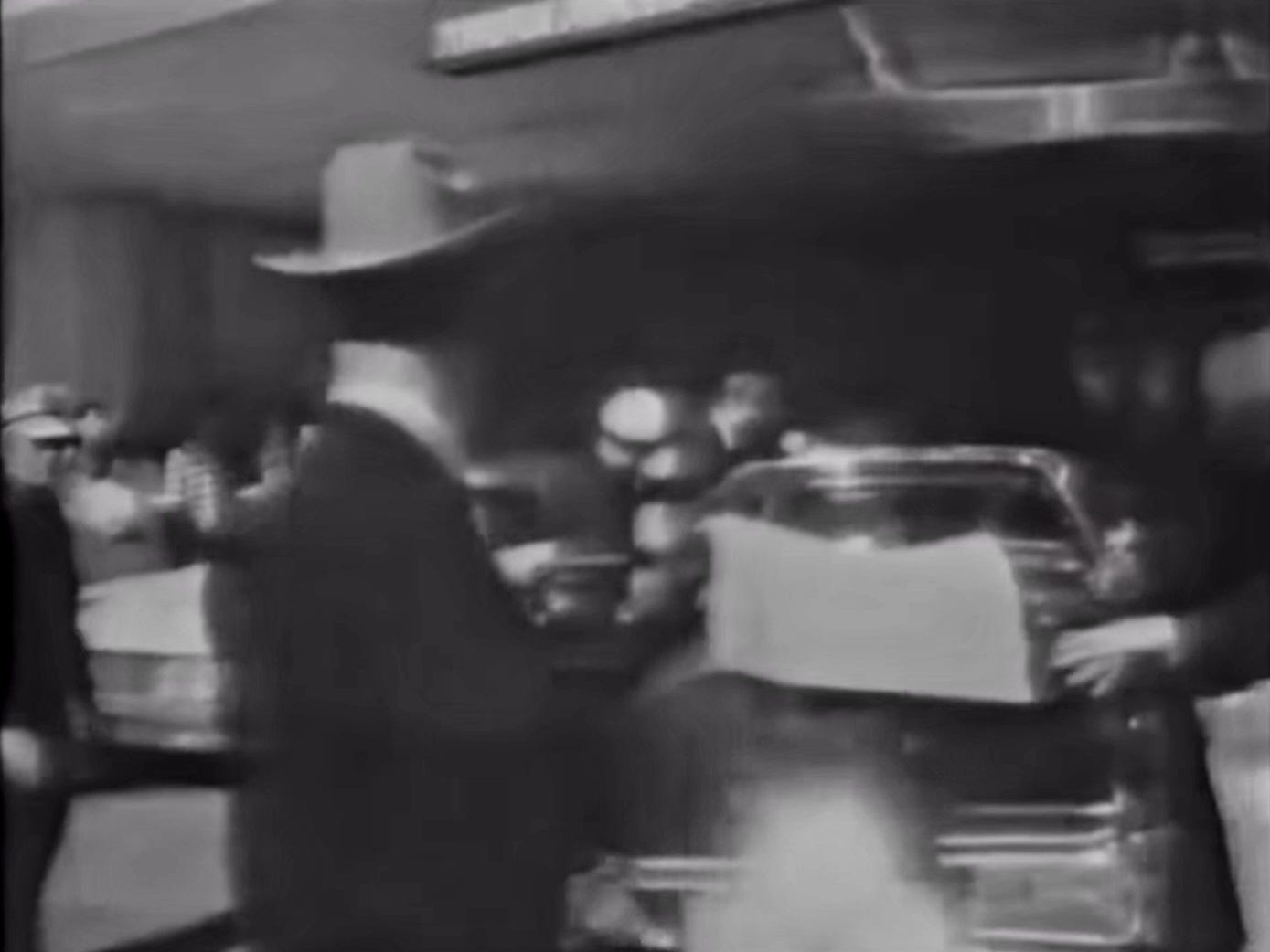 Frame from the Wiegman film showing fabric coverings being placed on the limousine's roof components just after the staff secretaries passed it.