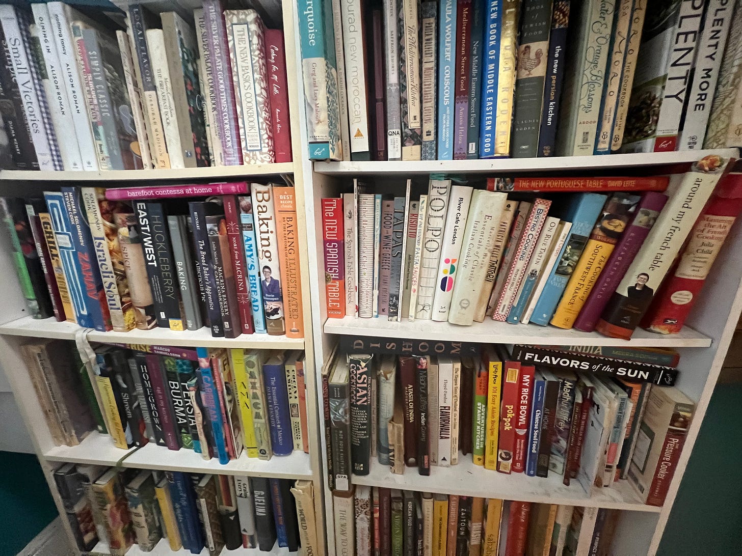 Collection of books on white bookshelves.