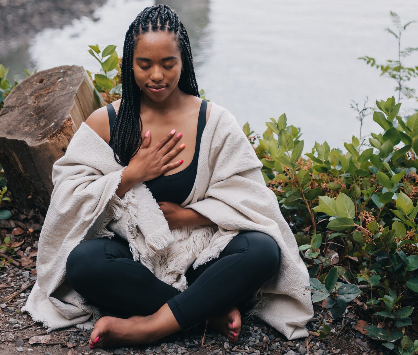 black woman with eyes closed sitting in front a lake mediating black woman with eyes closed sitting in front a lake mediating