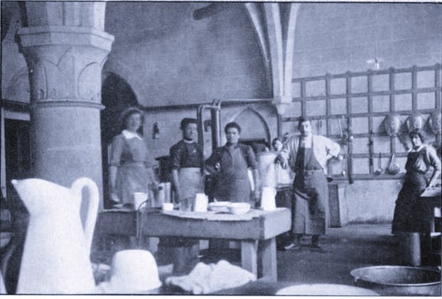 A black  and white photograph showing the kitchen at the Scottish Women's Hospital at Royaumont during WWI, with the staff, including Jeanne Desbordes the head cook (3rd from left), and the chef Michelet, the only man working at Royaumont.