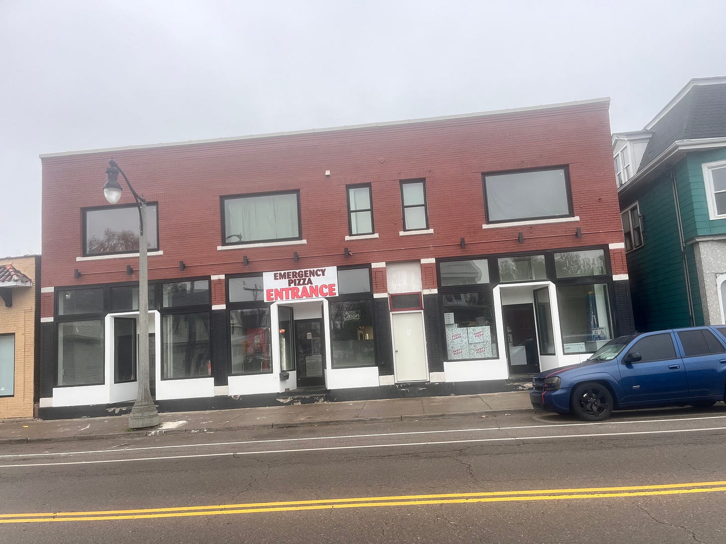 Brick building with a simple but dramatic sign that reads, "Emergency Pizza Entrance."