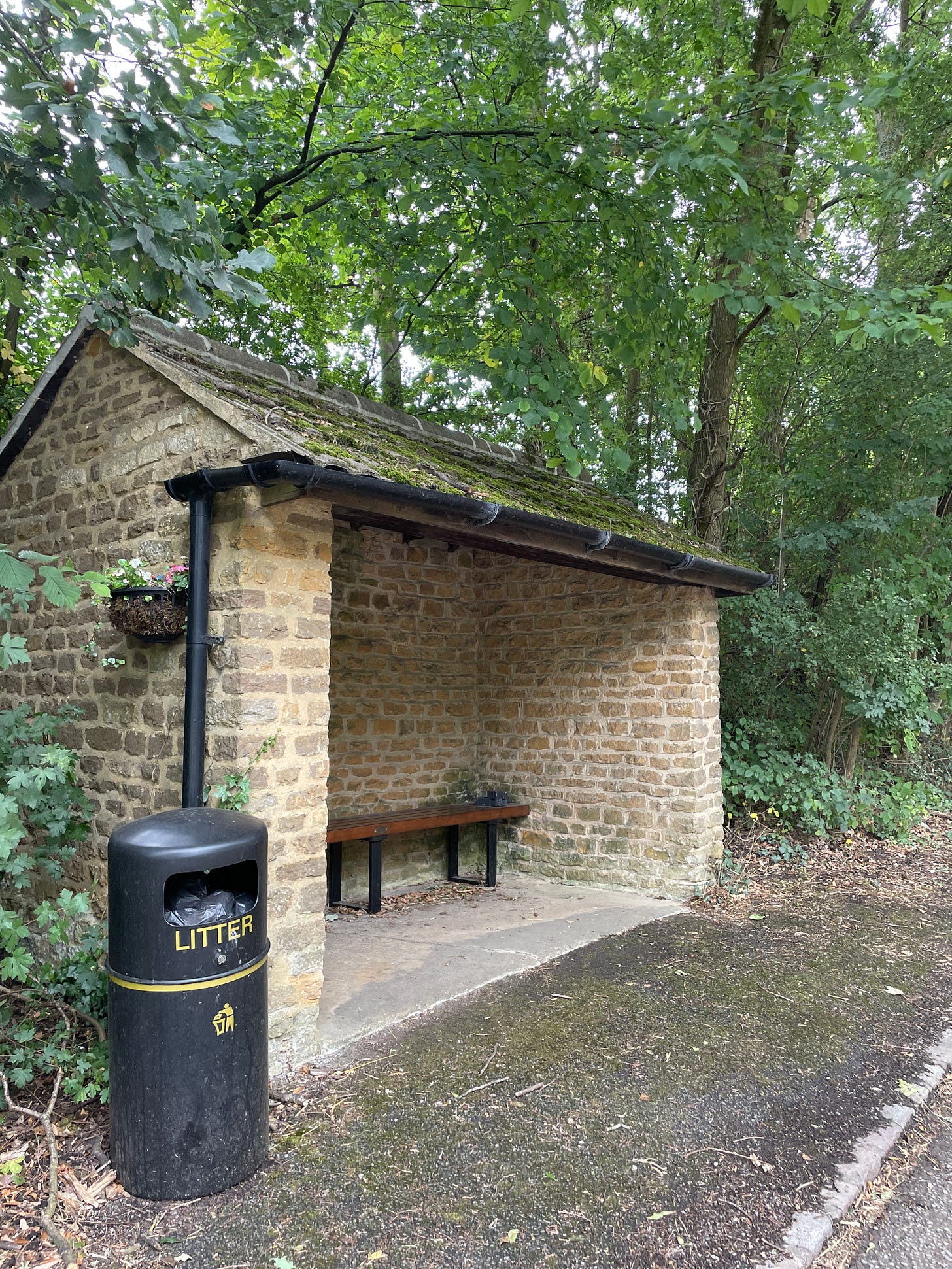 A brick bus shelter in a wooded area.