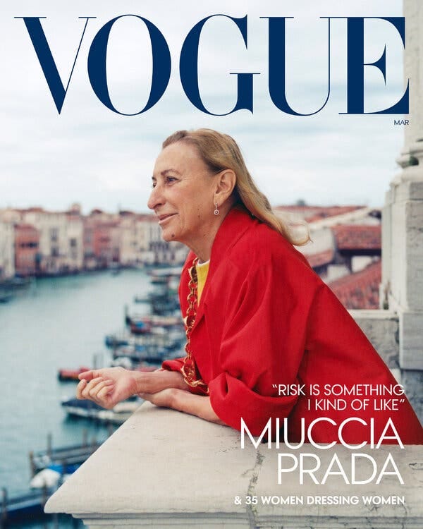 Vogue magazine cover featuring a woman in a red coat, staring off into the distance. She leans on a balcony overlooking a canal in Venice.