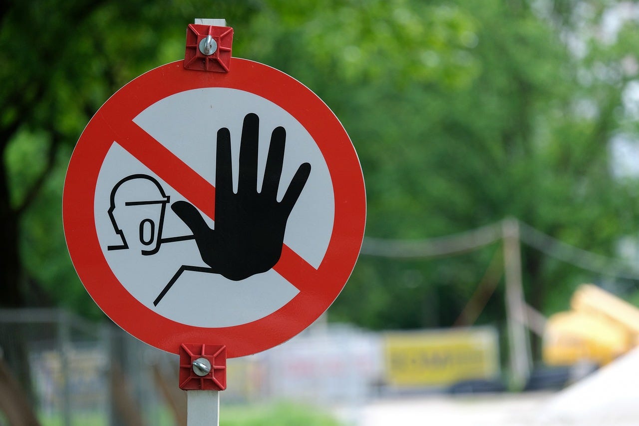 A street sign with a construction worker gesturing to halt