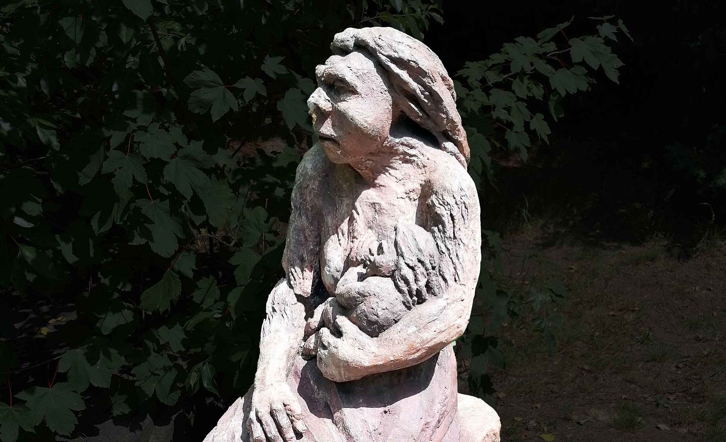 A concrete sculpture showing a Neandertal woman with child at breast A concrete sculpture showing a Neandertal woman with child at breast