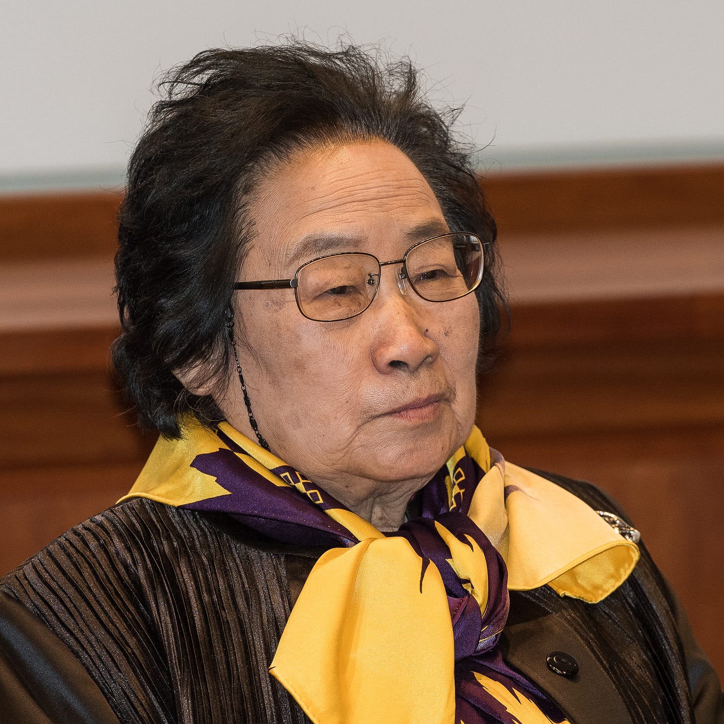 An image of Chinese scientist Tu Youyou in academic regalia seated at a table.