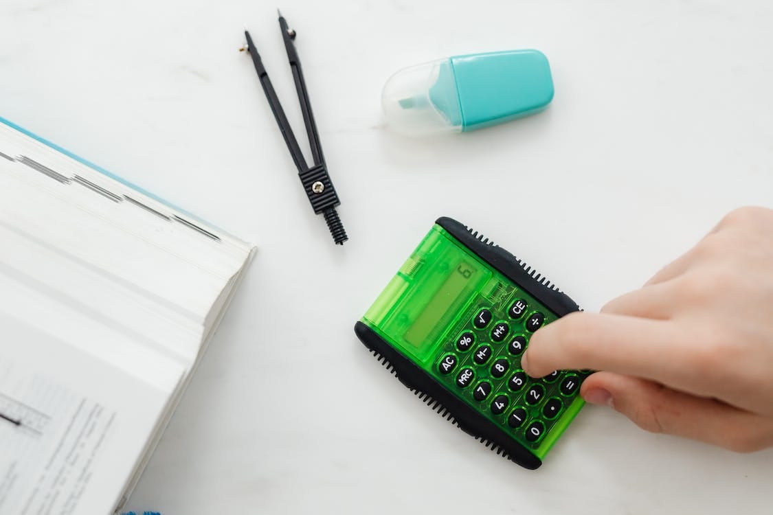 Free Person Using A Small Green and Black Calculator Stock Photo