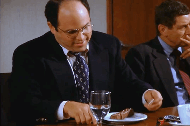 GIF of George Costanza eating a Snickers bar with a knife and fork