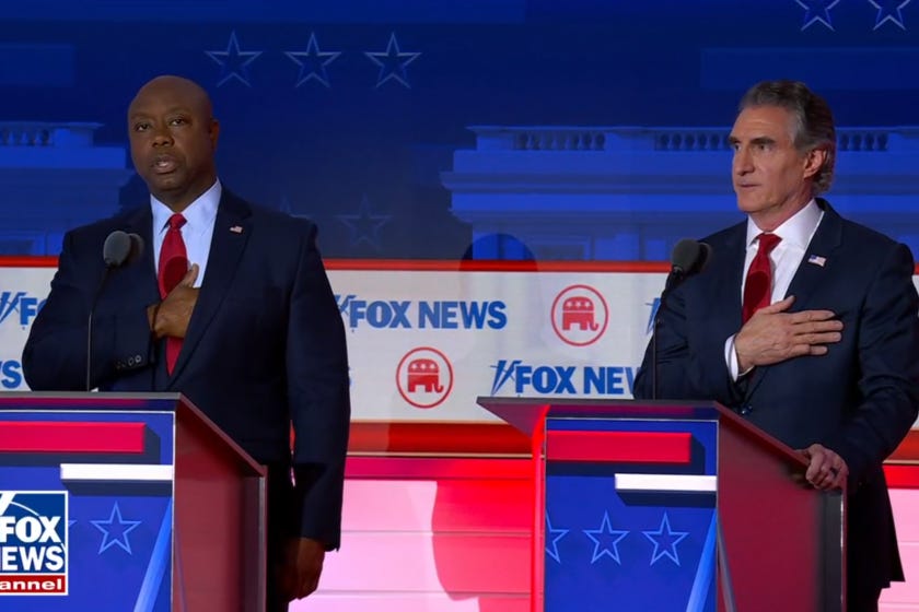 Gov. Doug Burgum stands next to Sen. Tim Scott of South Carolina during the performance of the national anthem at the beginning of the GOP's first presidential debate broadcast on Fox News on August 23, 2023.