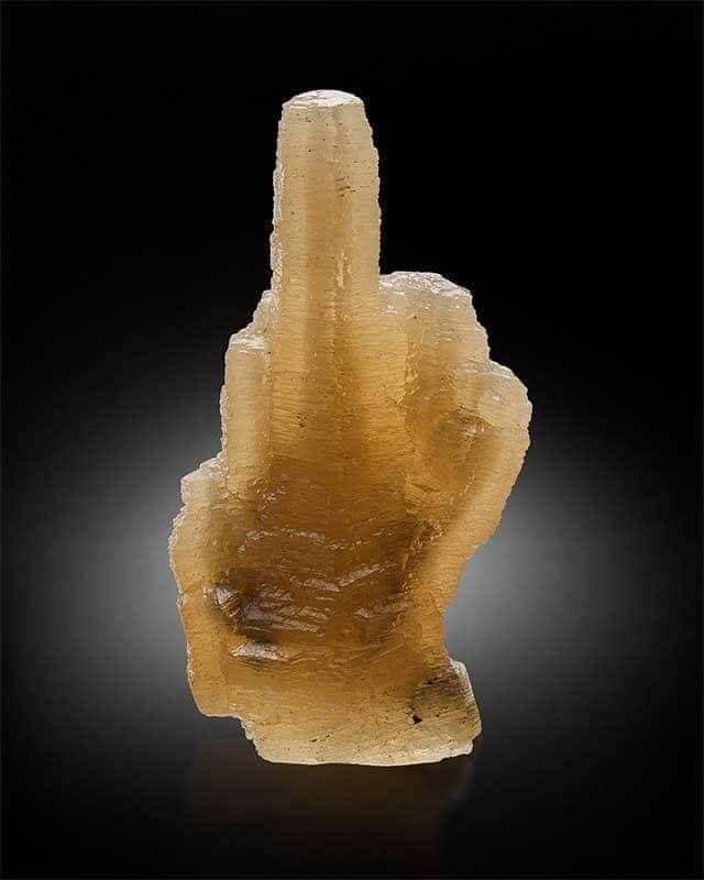 I believe this is a calcite but I can't remember where I found this image. Its a yellow rock in the shape of a middle finger.