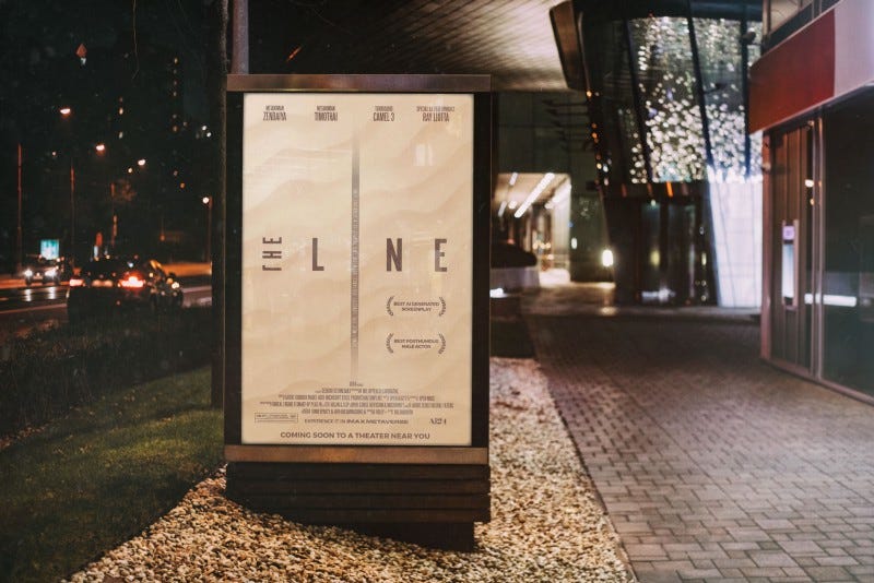 A movie poster for the Line in a bus shelter ad panel at night near a movie theater.