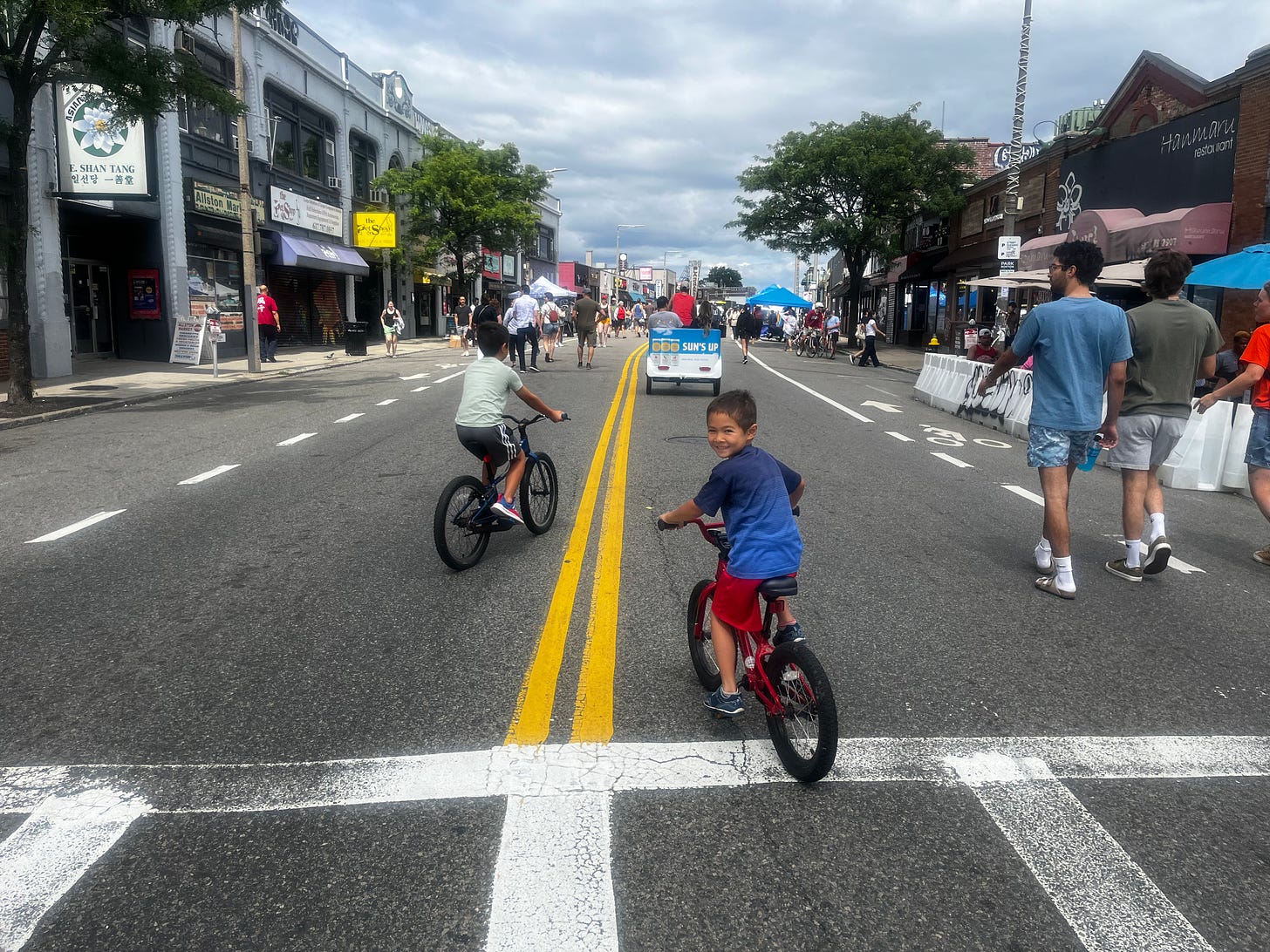 Blaise and Cass ride their bikes in the middle of Harvard Ave in Allston for the Open Streets event