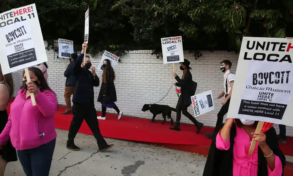 Nine or ten striking union workers outdoors, wearing masks, protest the Chateau Marmont with picket signs that read, “UNITEHERE! LOCAL 11 Boycott Chateau Marmont. This hotel does not have a union contract with UNITE HERE Local 11."