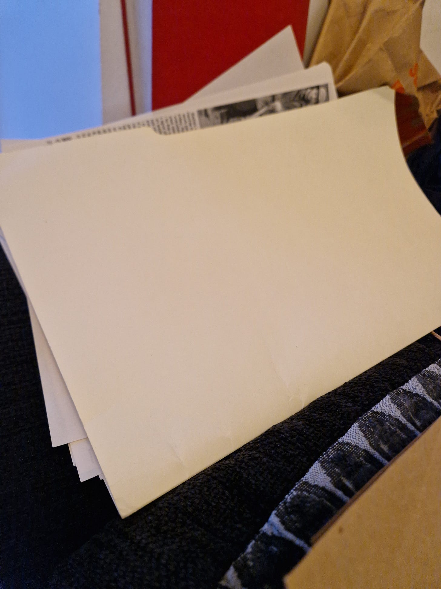 A cream coloured folder holding a lot of newspaper clippings for digitising and cataloguing