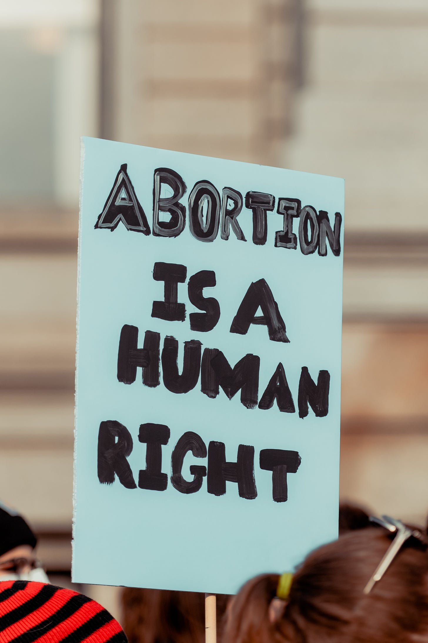 A close-up of a hand written sign. The sign says ‘Abortion Is A Human Right’.