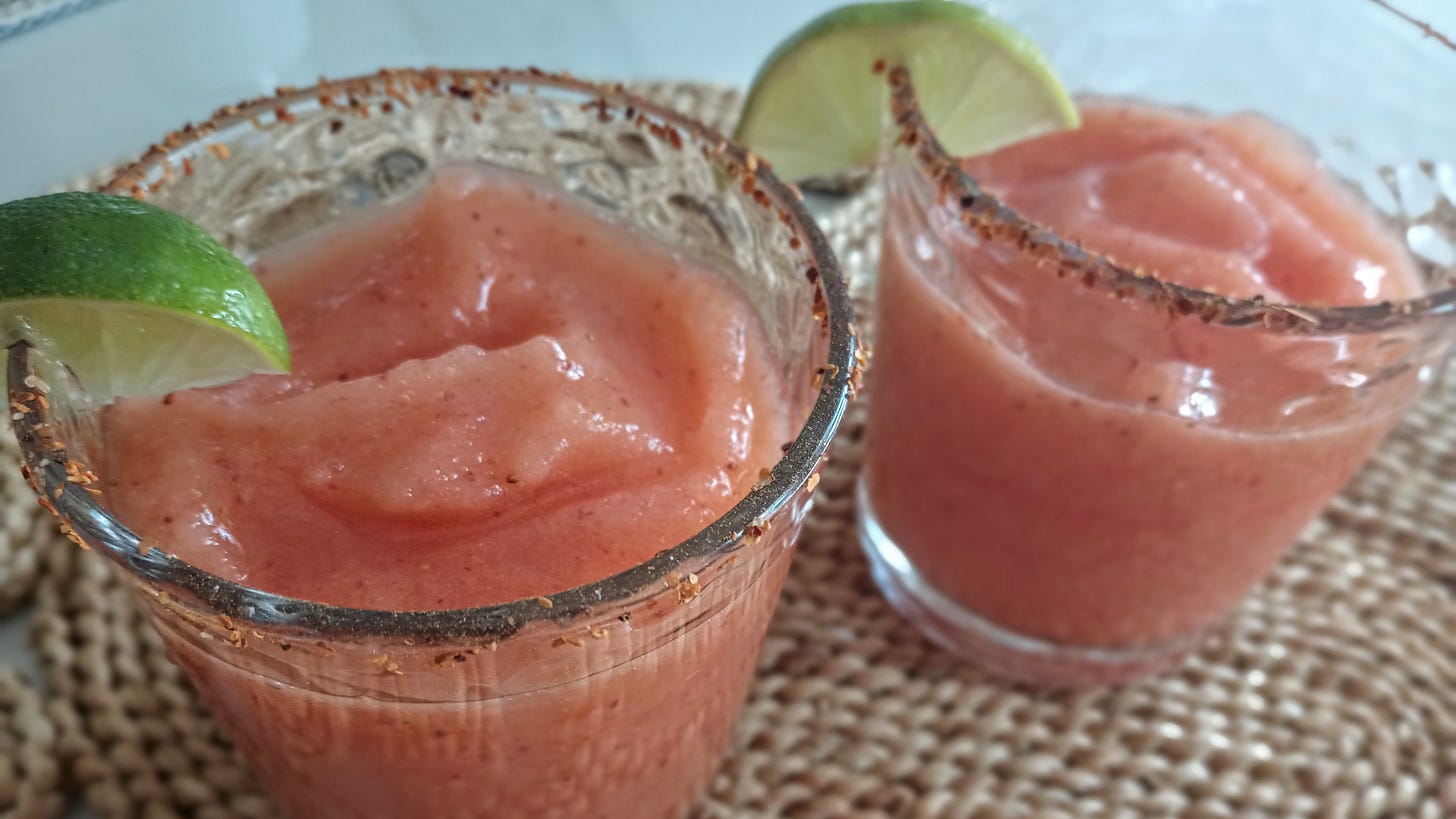 2 pink blended drinks in glasses with line slices on woven placemat.