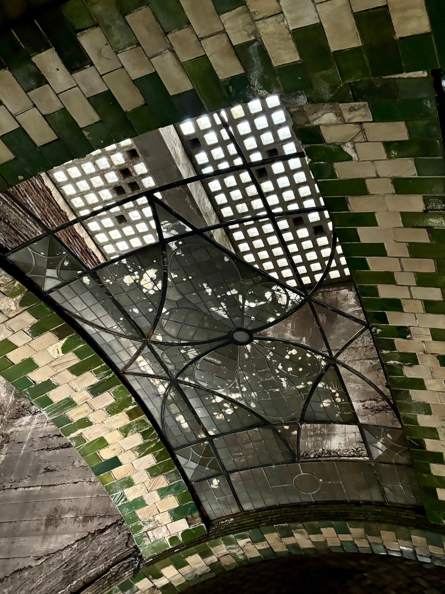 A tiled glass window in the green and white tile ceiling.