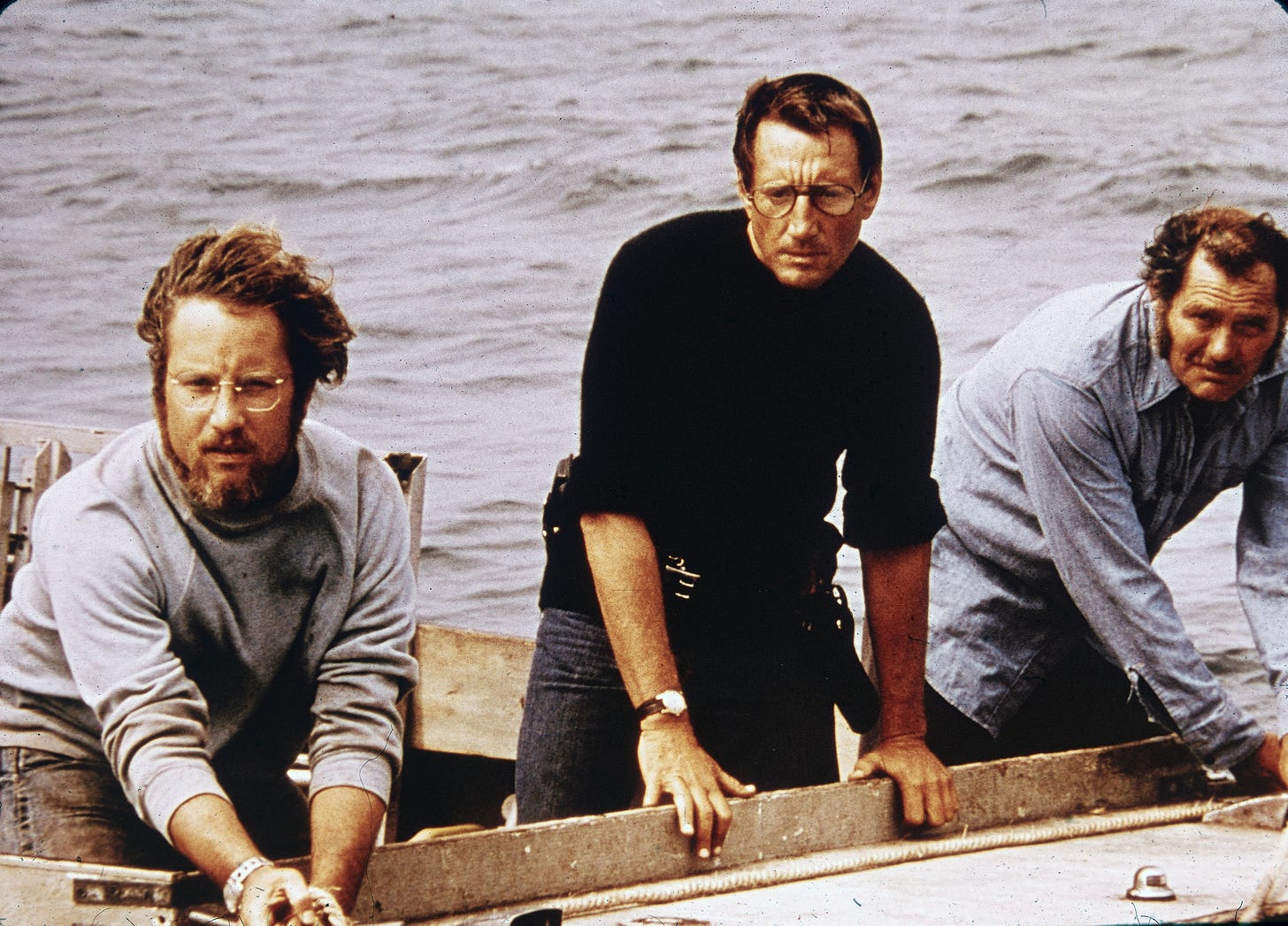 Three men in a boat wear looks of concern