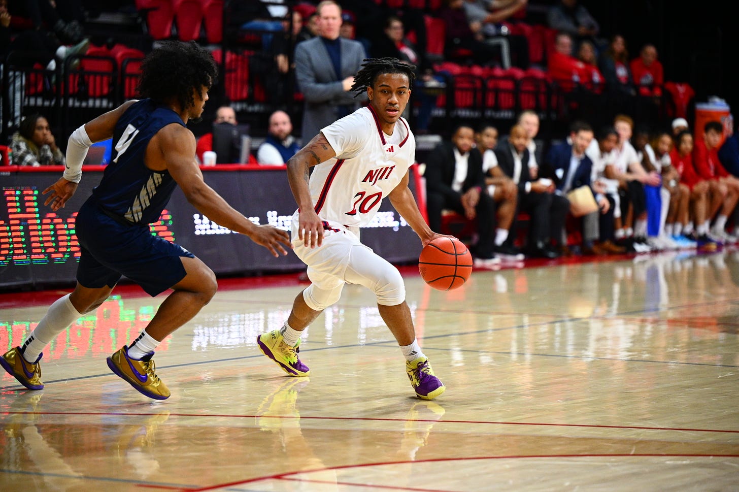 Tariq Francis drives with the ball while NJIT coach Grant Billmeier (back, center) looks on during a game against New Hampshire on Jan. 18, 2024. (Photo courtesy of NJIT Athletics)