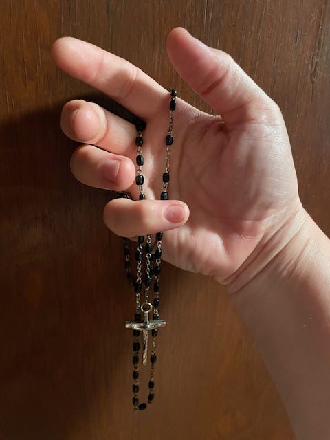 A right hand holding a rosary.  