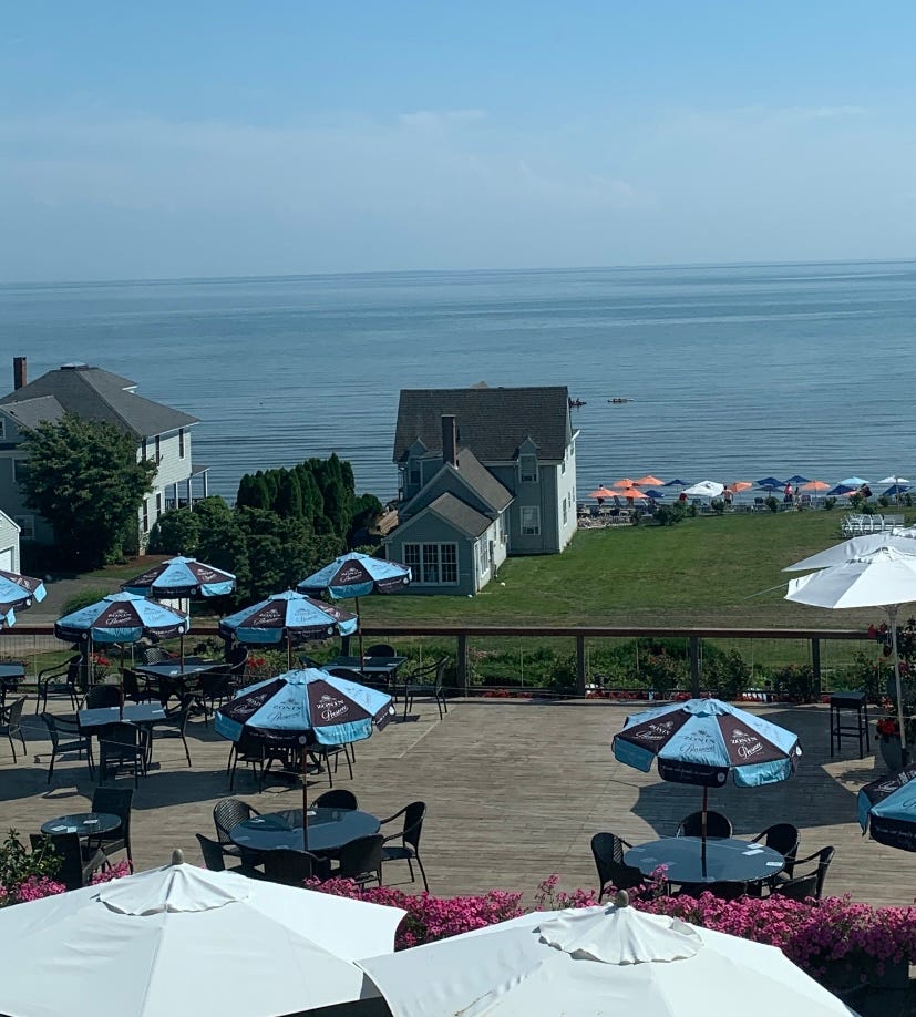 A patio with blue and black umbrellas overlooking the ocean. 