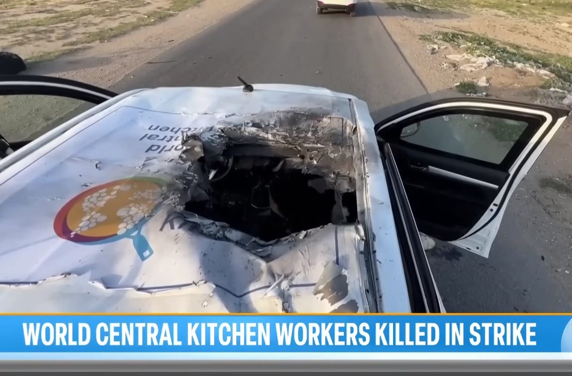 Screenshot of video showing a World Central Kitchen SUV hit by a missile that went through its roof, with part of the large WCF logo still visible next to the charred entry hole
