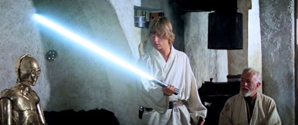 From Star Wars, Obi-Wan Kenobi sits at home and watches as Luke Skywalker turns on a lightsaber for the first time. Luke examines his father's lightsaber.