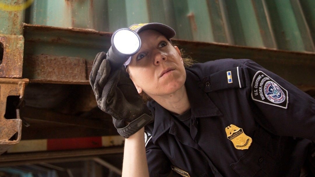 A US Customs & Border Protection Officer checks the underside of a truck for hidden cargo. A US Customs & Border Protection Officer checks the underside of a truck for hidden cargo.